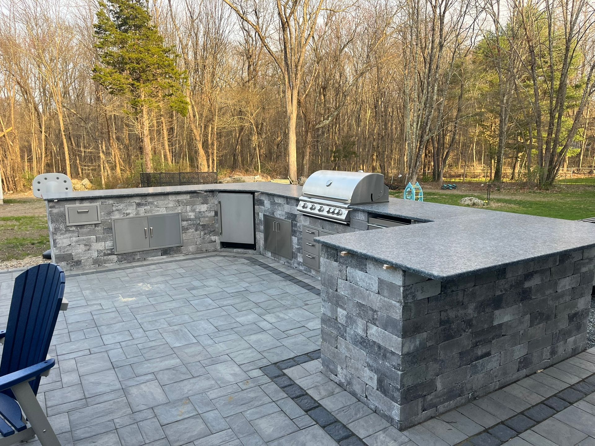 A large outdoor kitchen with a grill and a blue chair.