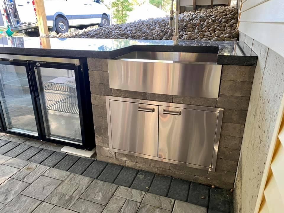 A stainless steel sink is built into a brick wall.