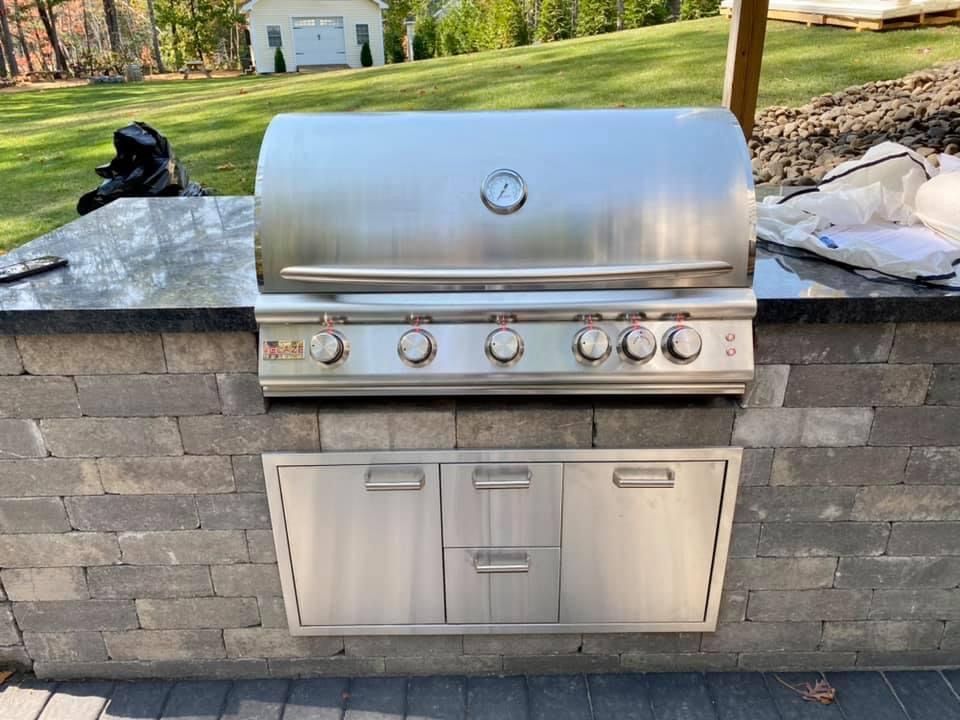 A stainless steel grill is mounted to a brick wall.