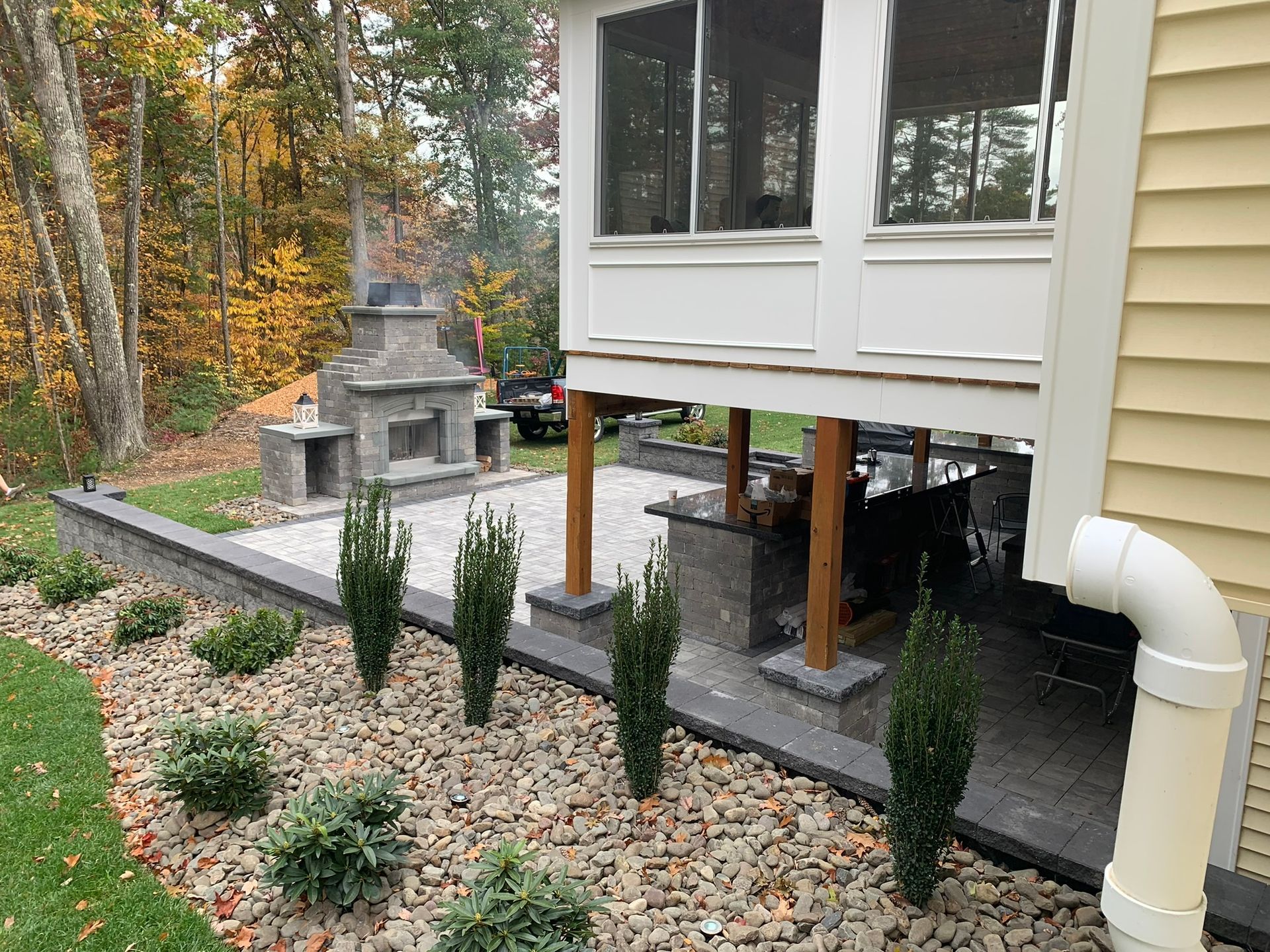A house with a screened in porch and a fireplace in the backyard.