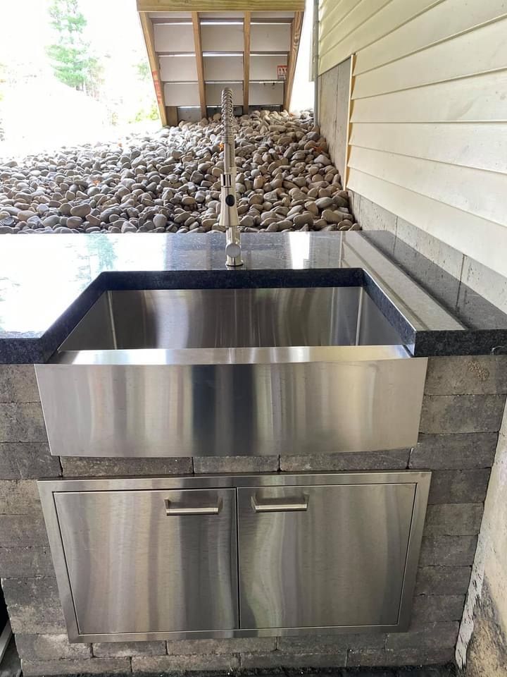 A stainless steel sink is built into a brick wall.