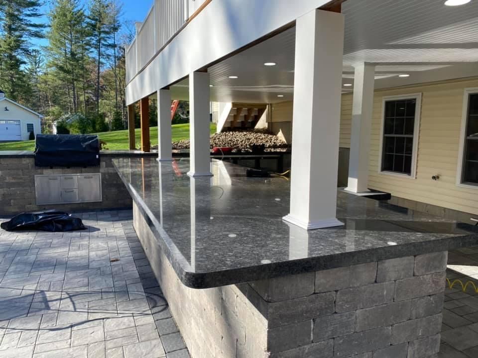 A patio with a large granite counter top and a grill.