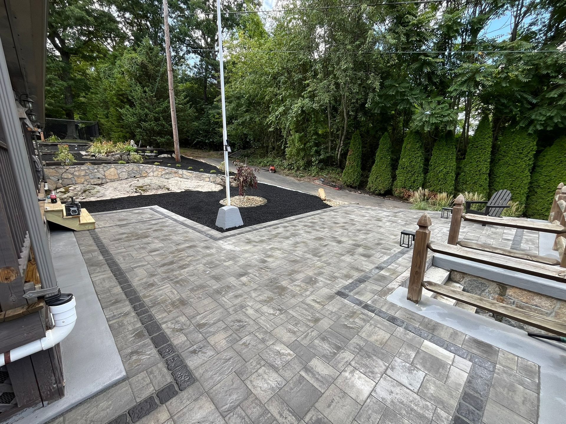 A large patio with a flag pole in the middle of it surrounded by trees.