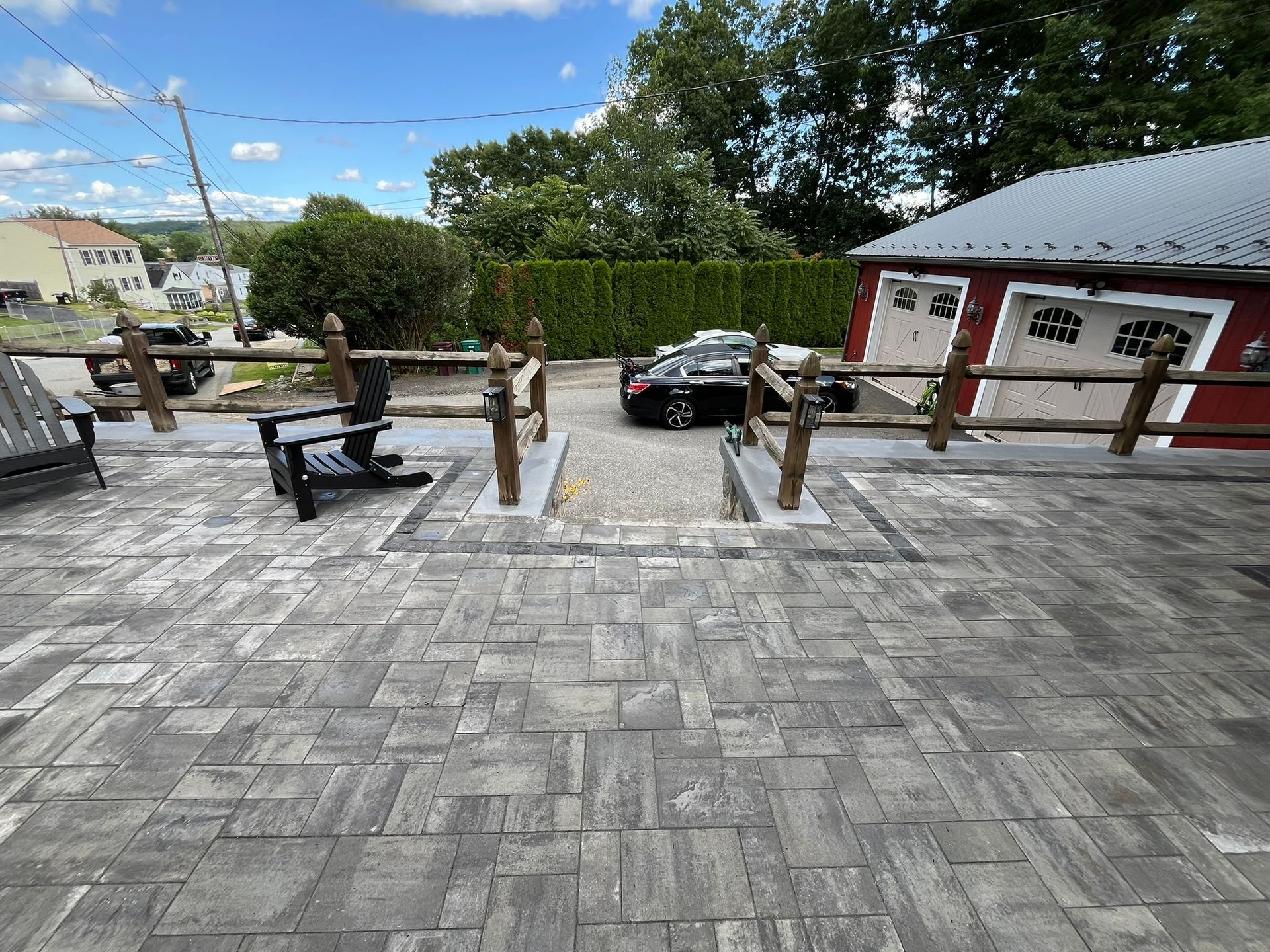 A patio with a wooden fence and chairs in front of a garage.
