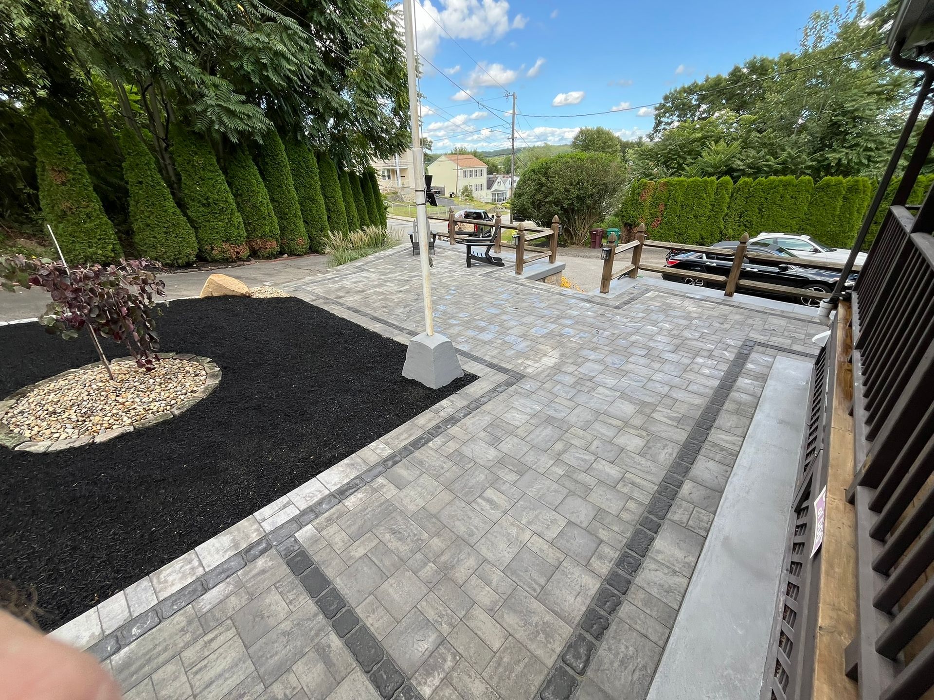 A patio with a flag pole in the middle of it and trees in the background.