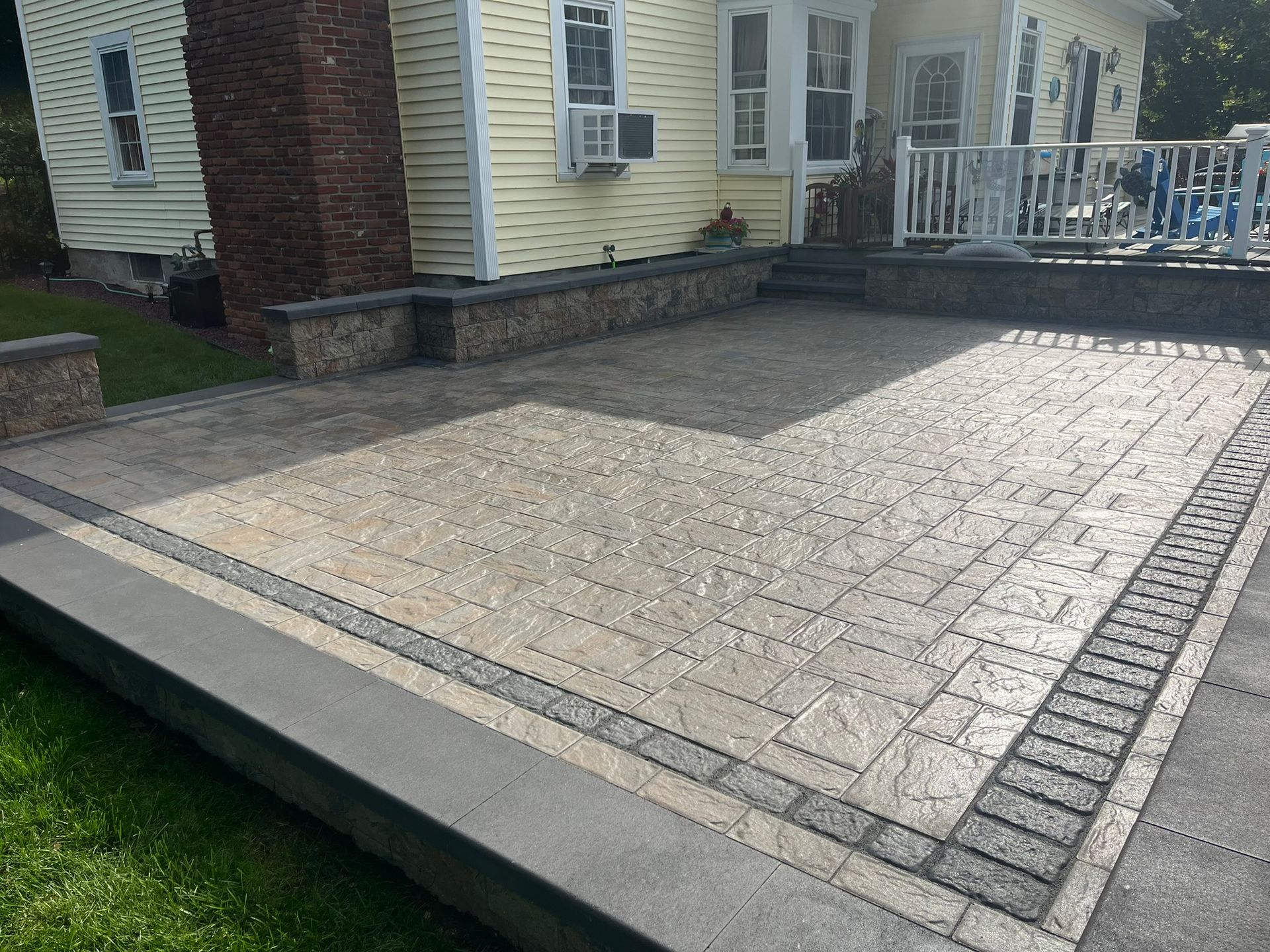 A patio with a brick walkway in front of a house.