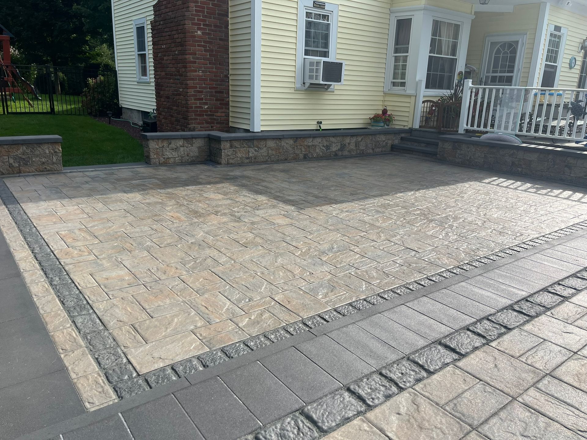 There is a brick driveway in front of a house.