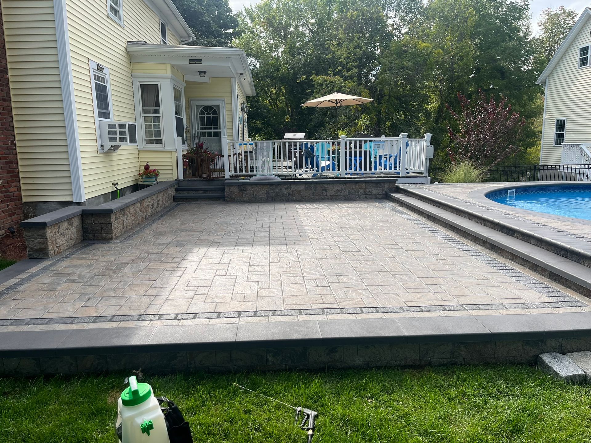 A patio with a swimming pool in the backyard of a house.