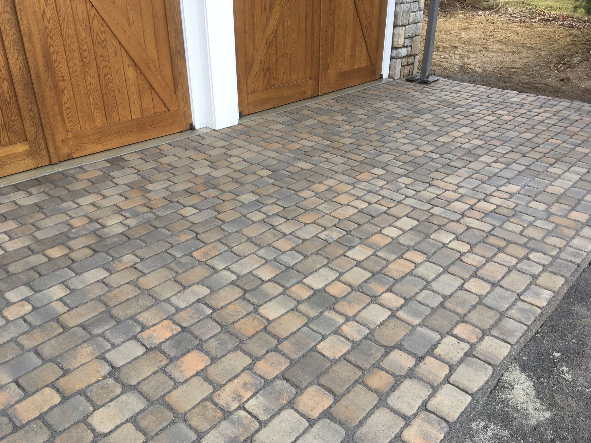 A brick driveway with a wooden garage door in the background.