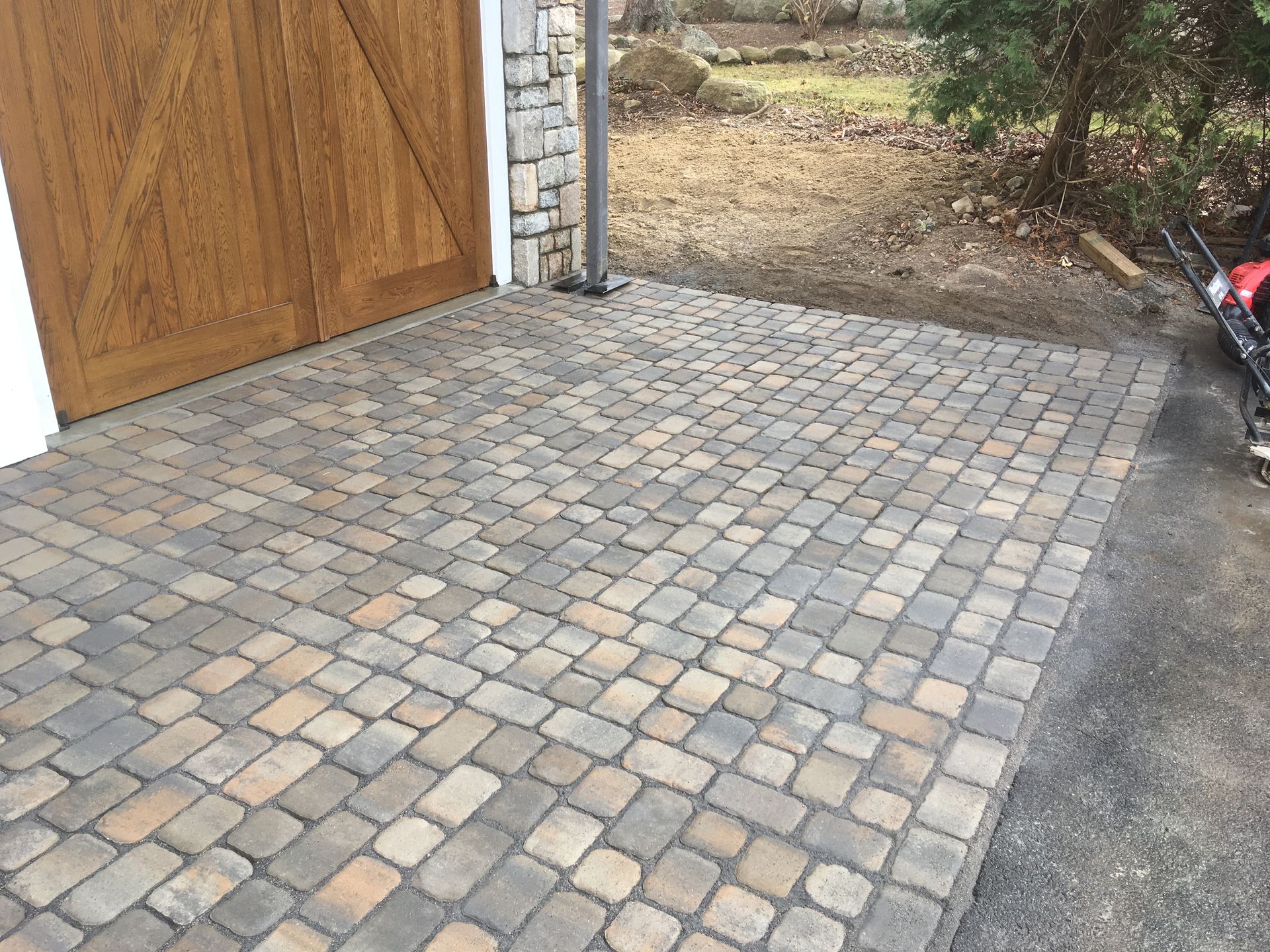 A nice-looking brick driveway with a wooden garage door in the background.