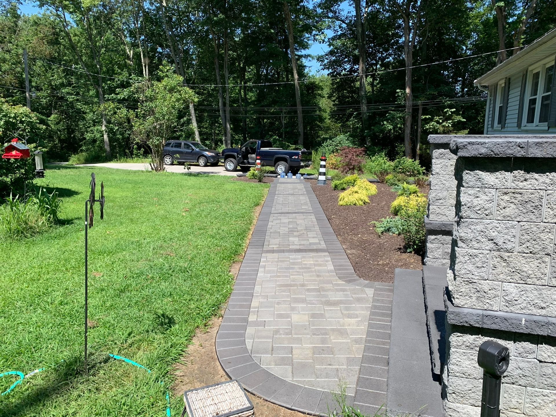 A walkway leading to a house with a car parked in the driveway.