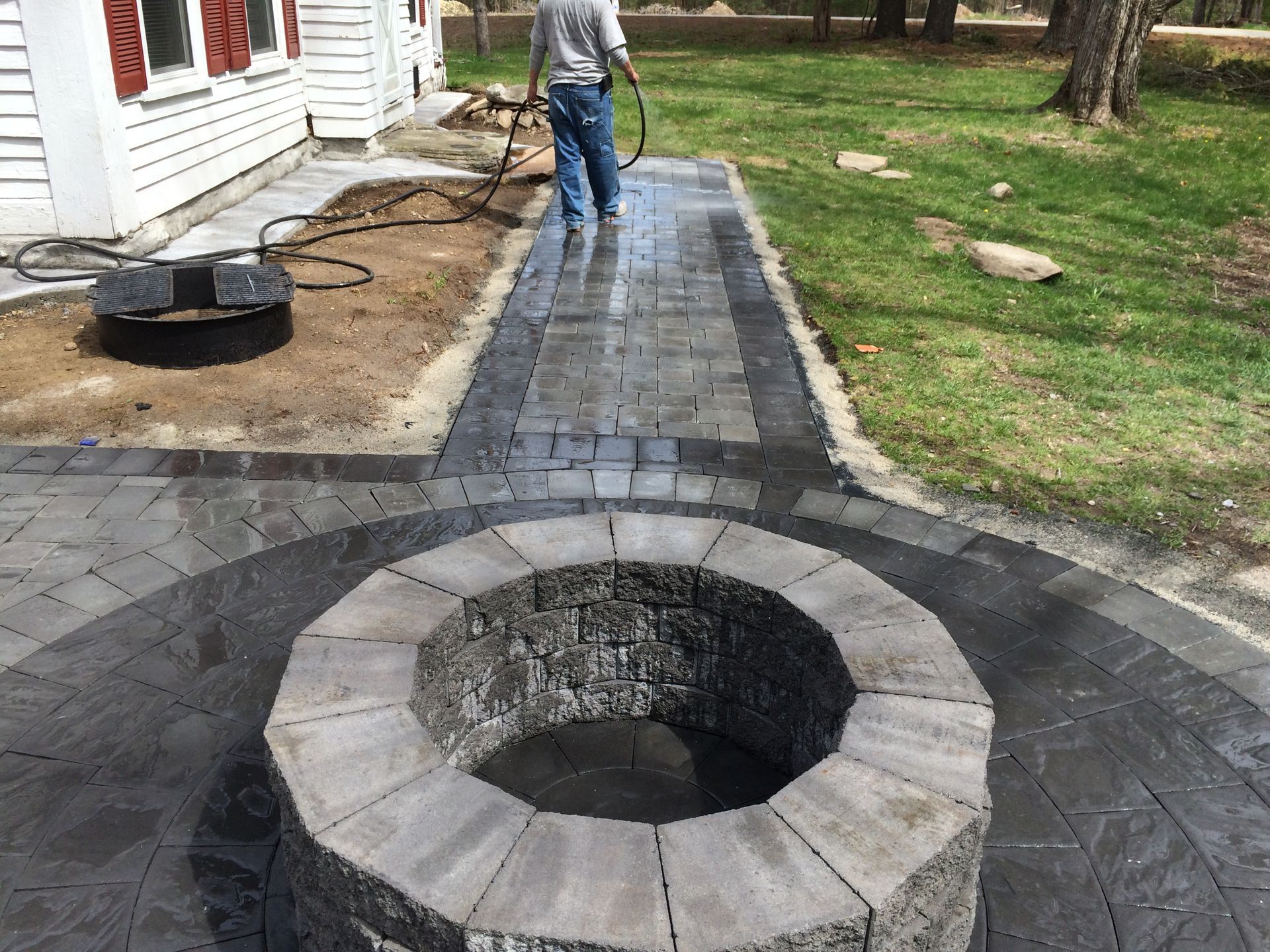 A man is standing next to a fire pit on a patio.