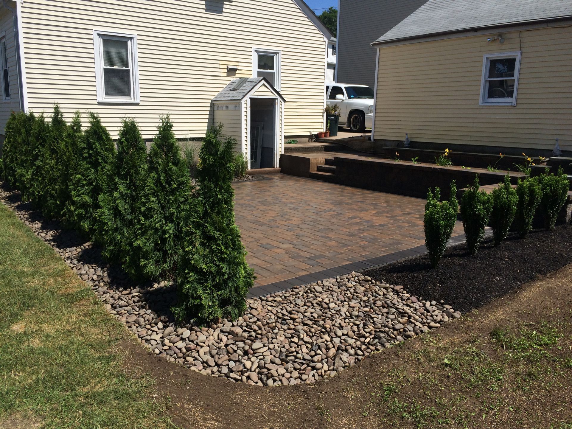 A house with a brick driveway and bushes in front of it
