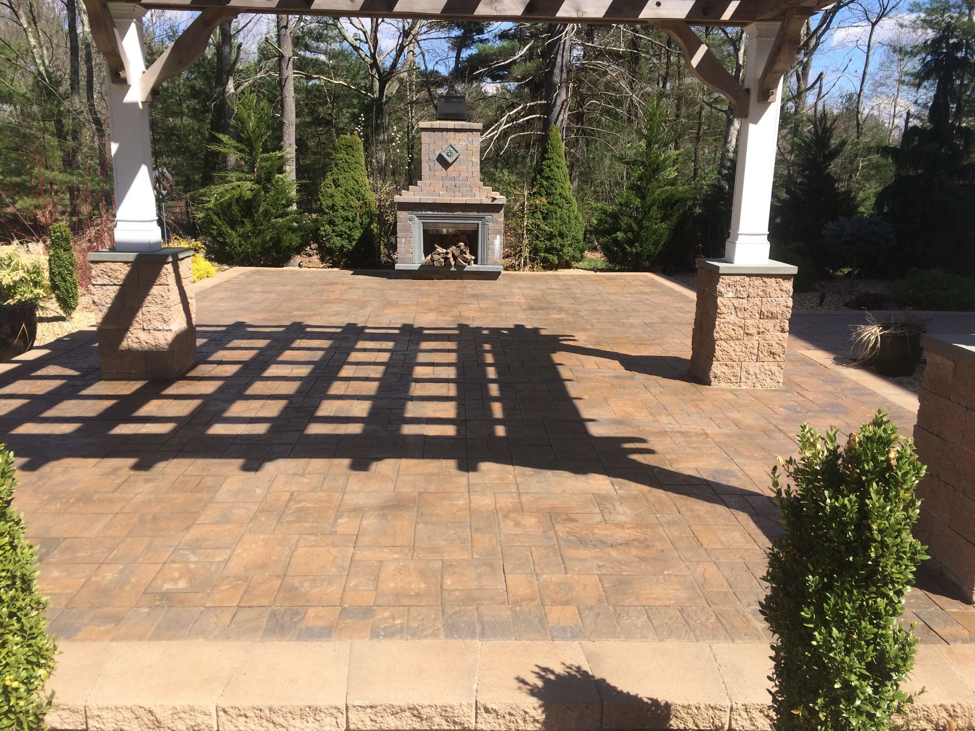 A patio with a fireplace and a pergola in the background.
