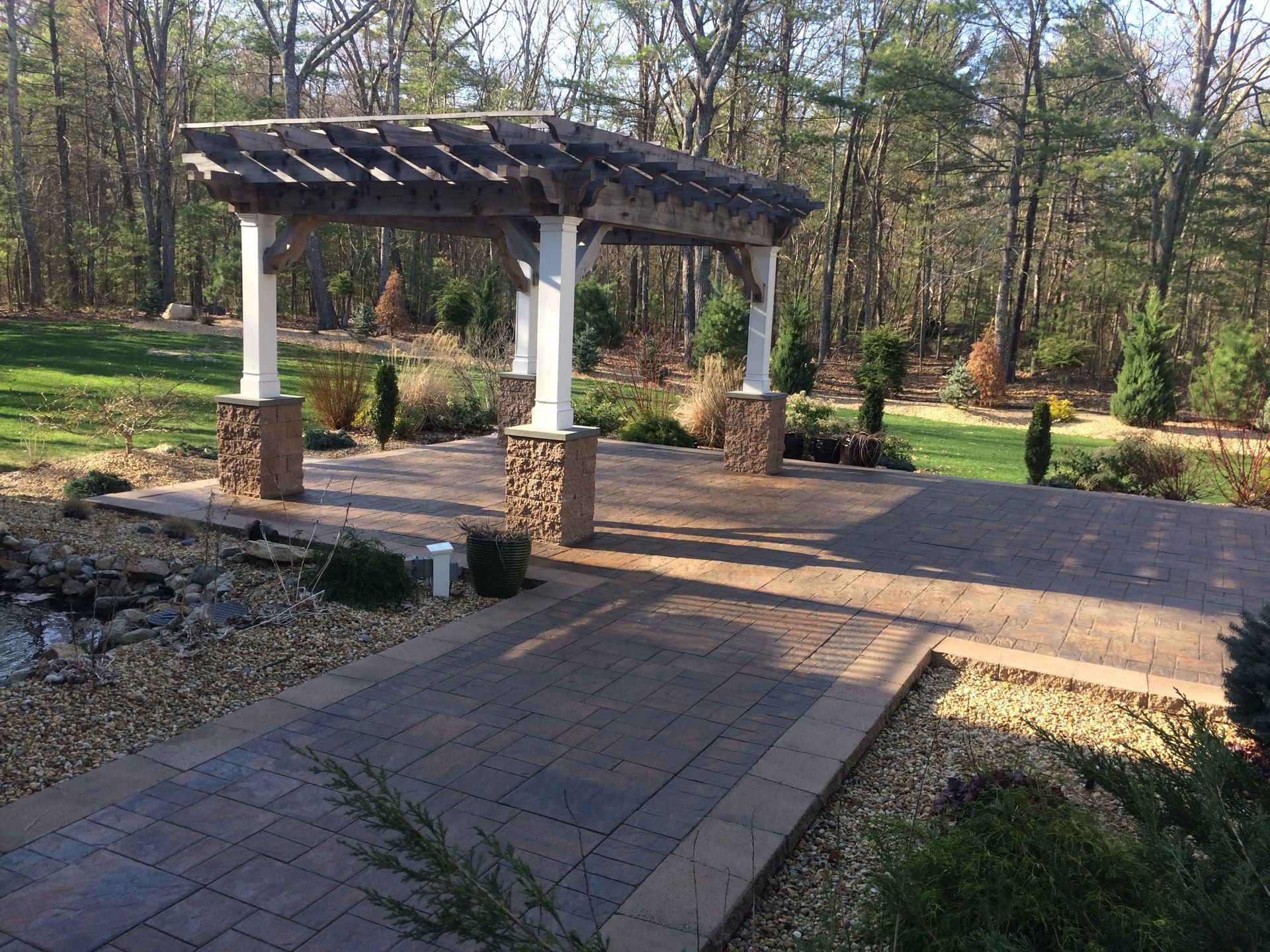 A patio with a pergola and trees in the background
