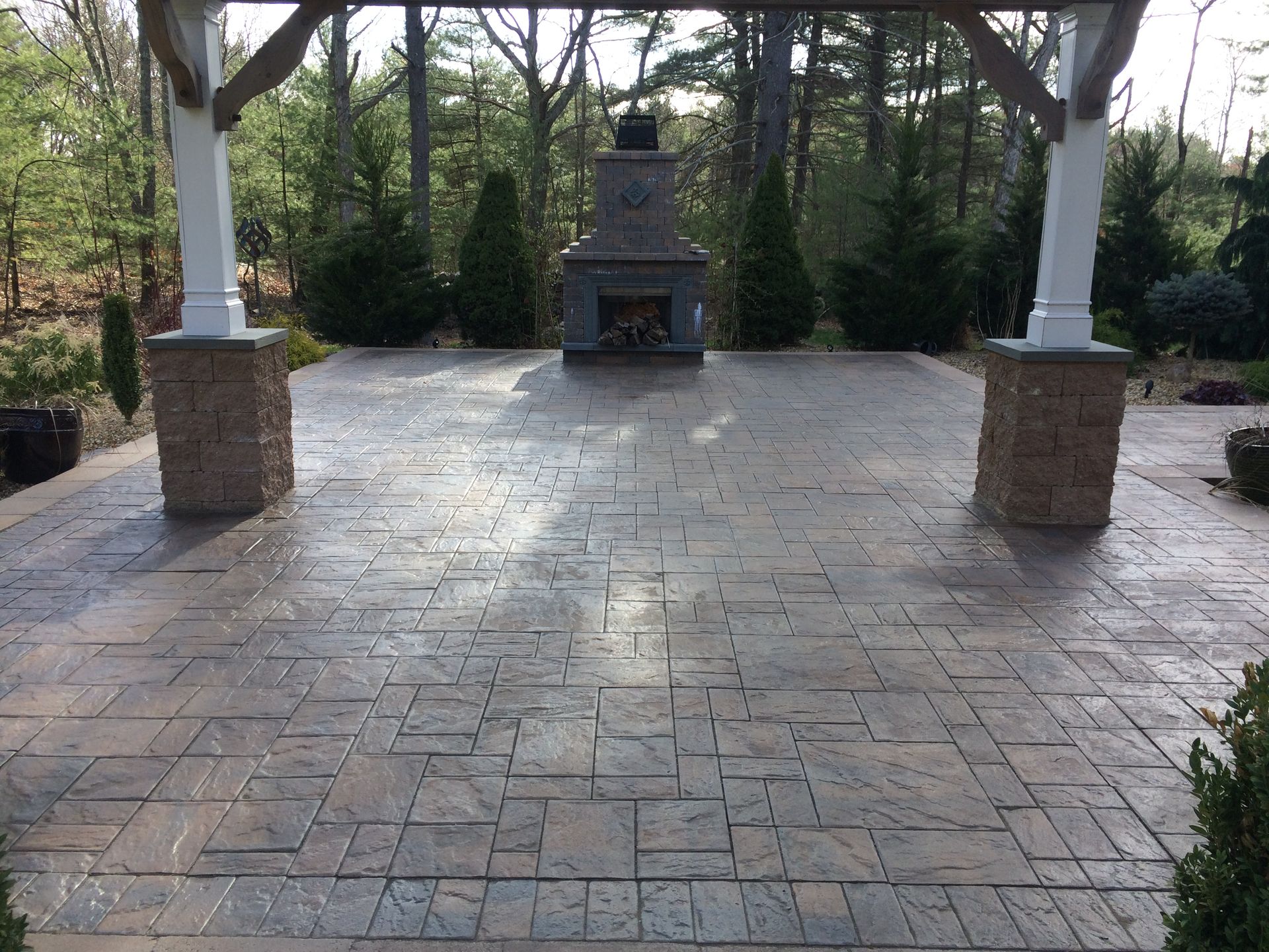 A patio with a fireplace and trees in the background
