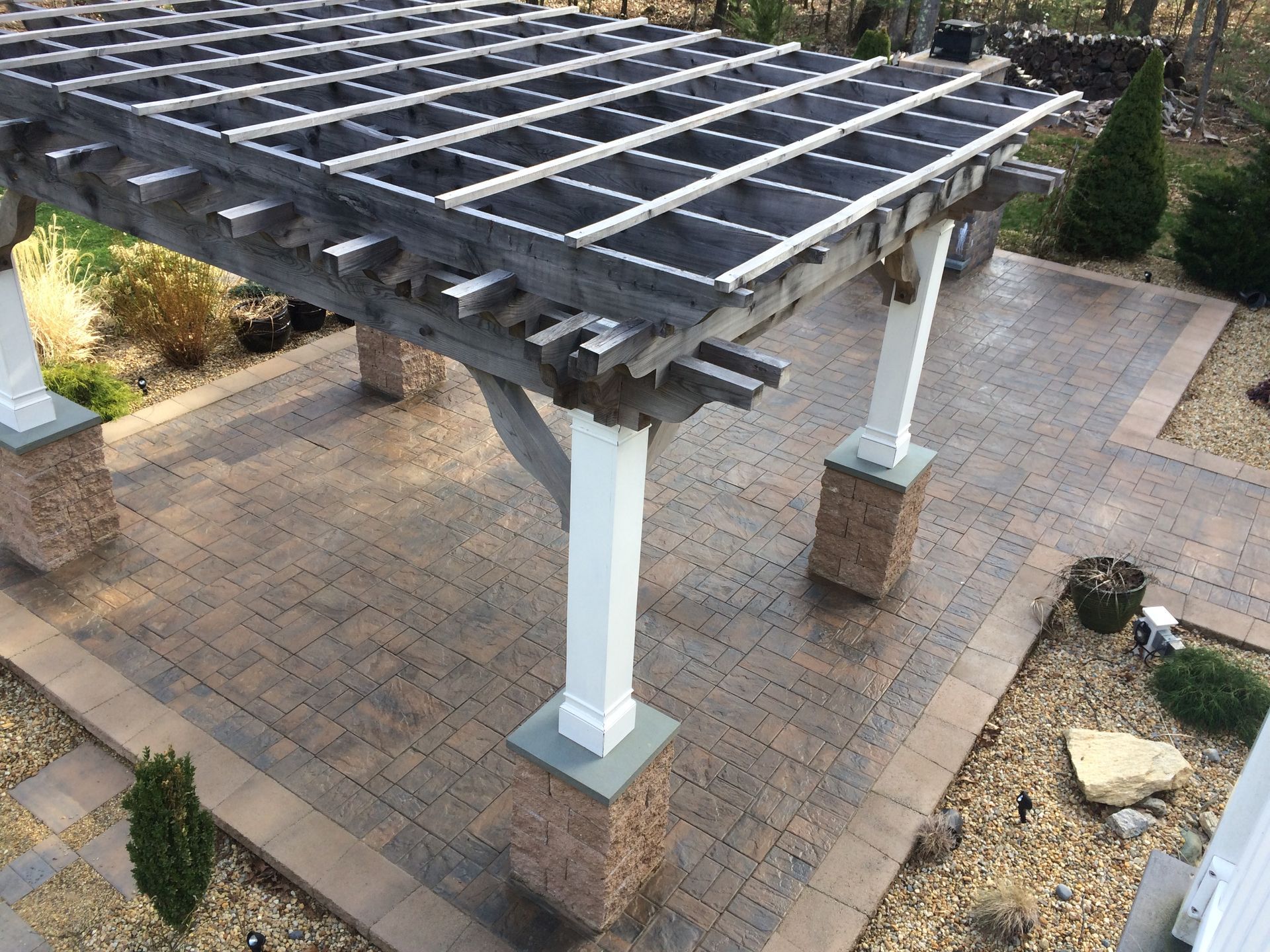 A wooden pergola is sitting on top of a brick patio.