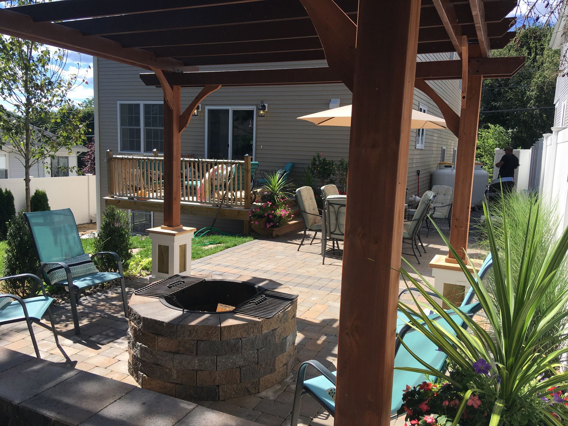 A patio with a fire pit and chairs under a pergola