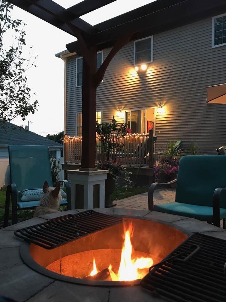 A fire pit on a patio with a house in the background