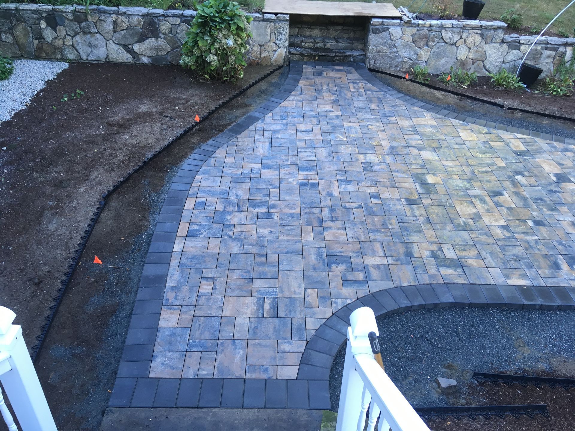 A brick walkway with a stone wall in the background