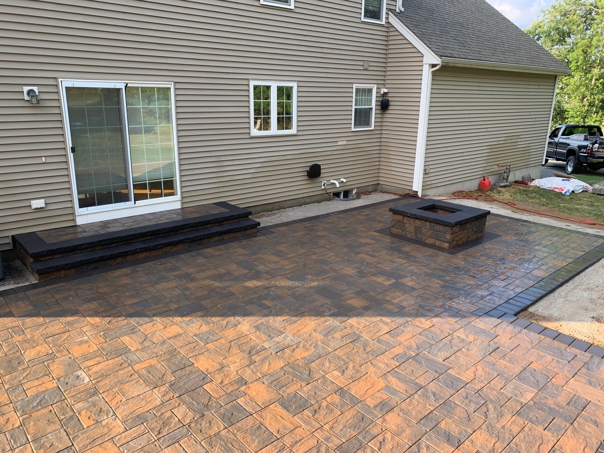 A patio with a fire pit in front of a house.