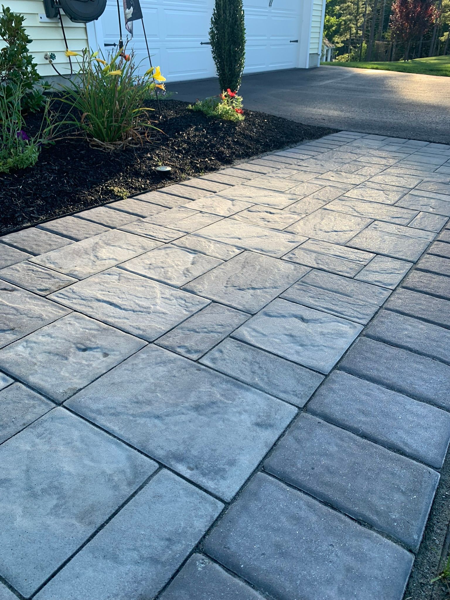 A driveway with a brick walkway leading to a garage.