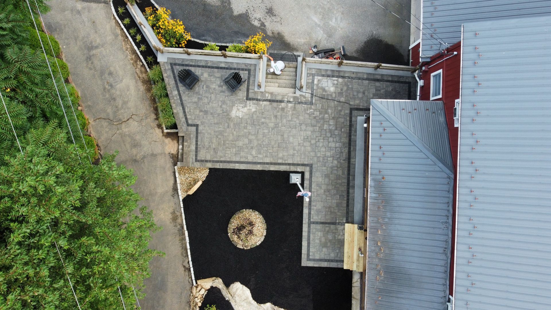 An aerial view of a patio with a fire pit and a house in the background.