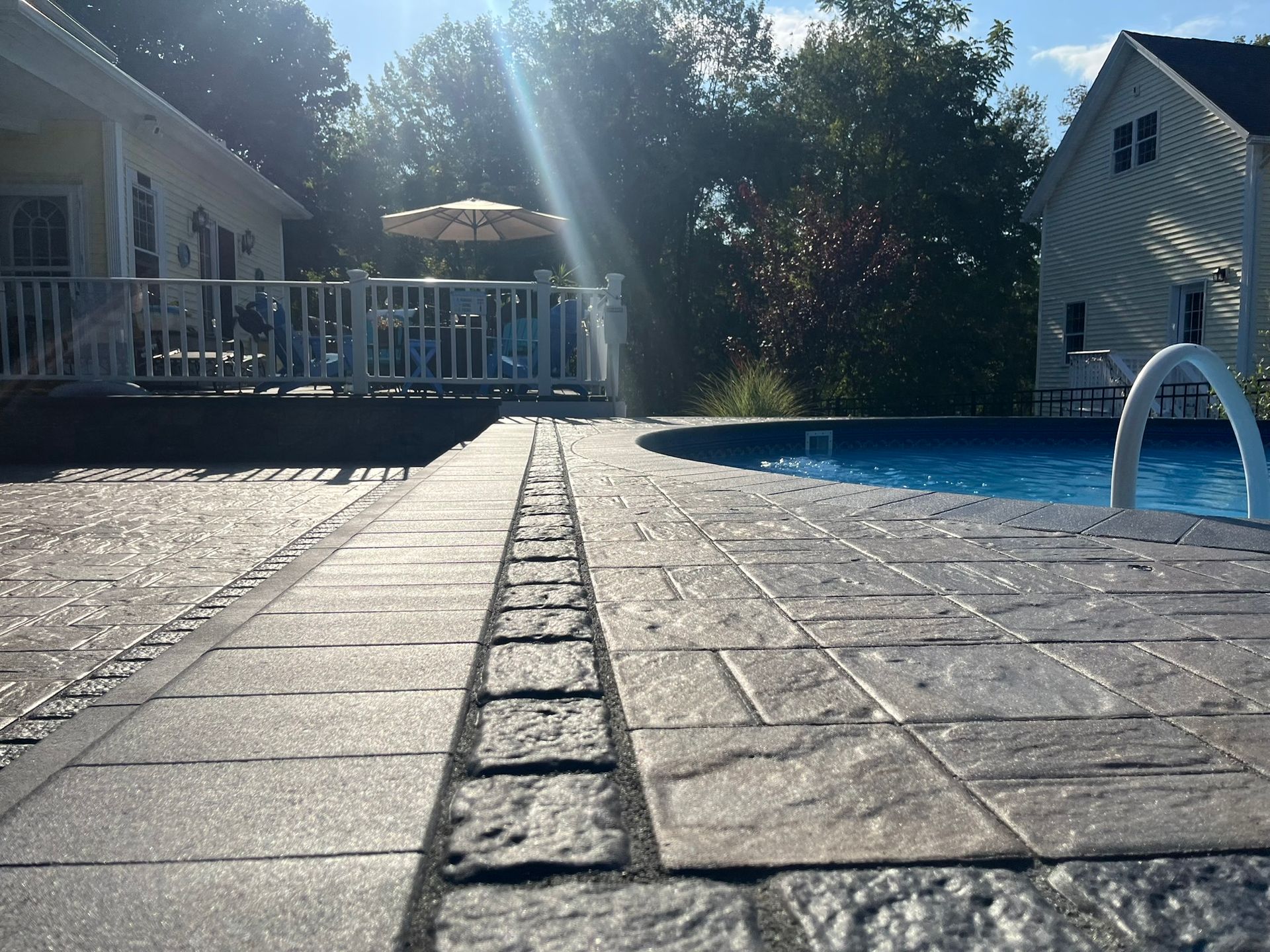 A swimming pool with a deck and a house in the background.