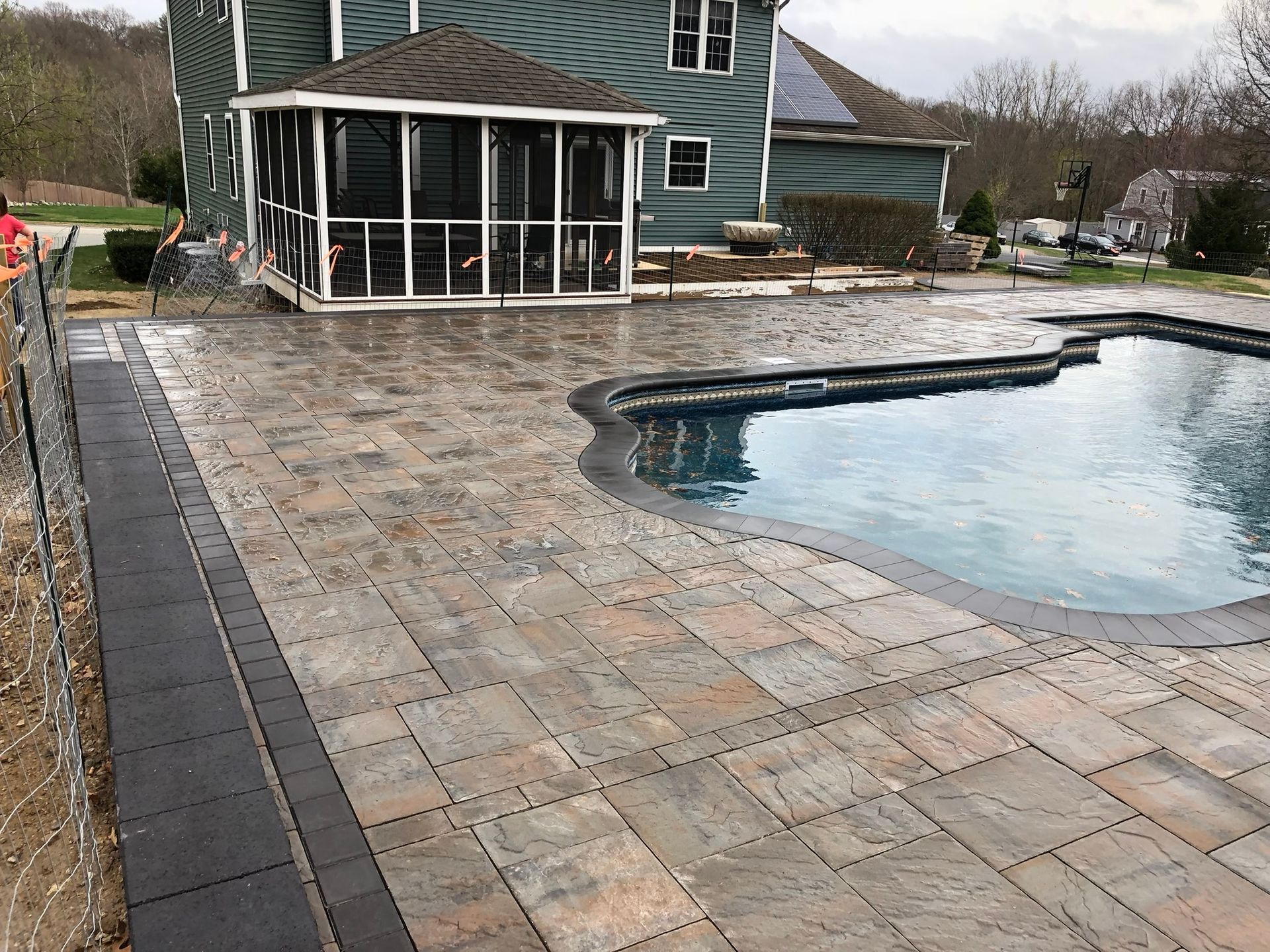 A patio with a screened in porch and a swimming pool in front of a house.