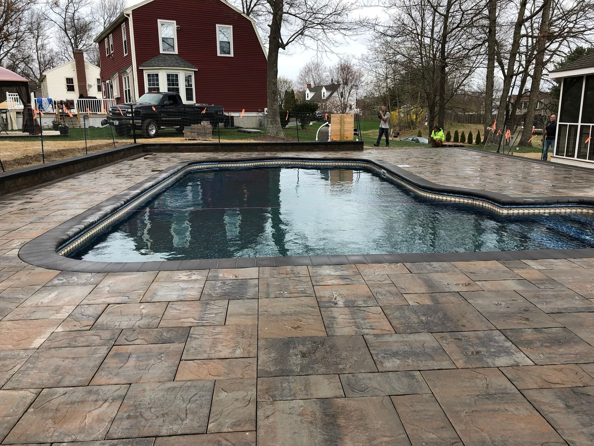 A large swimming pool is surrounded by a patio and a house in the background.