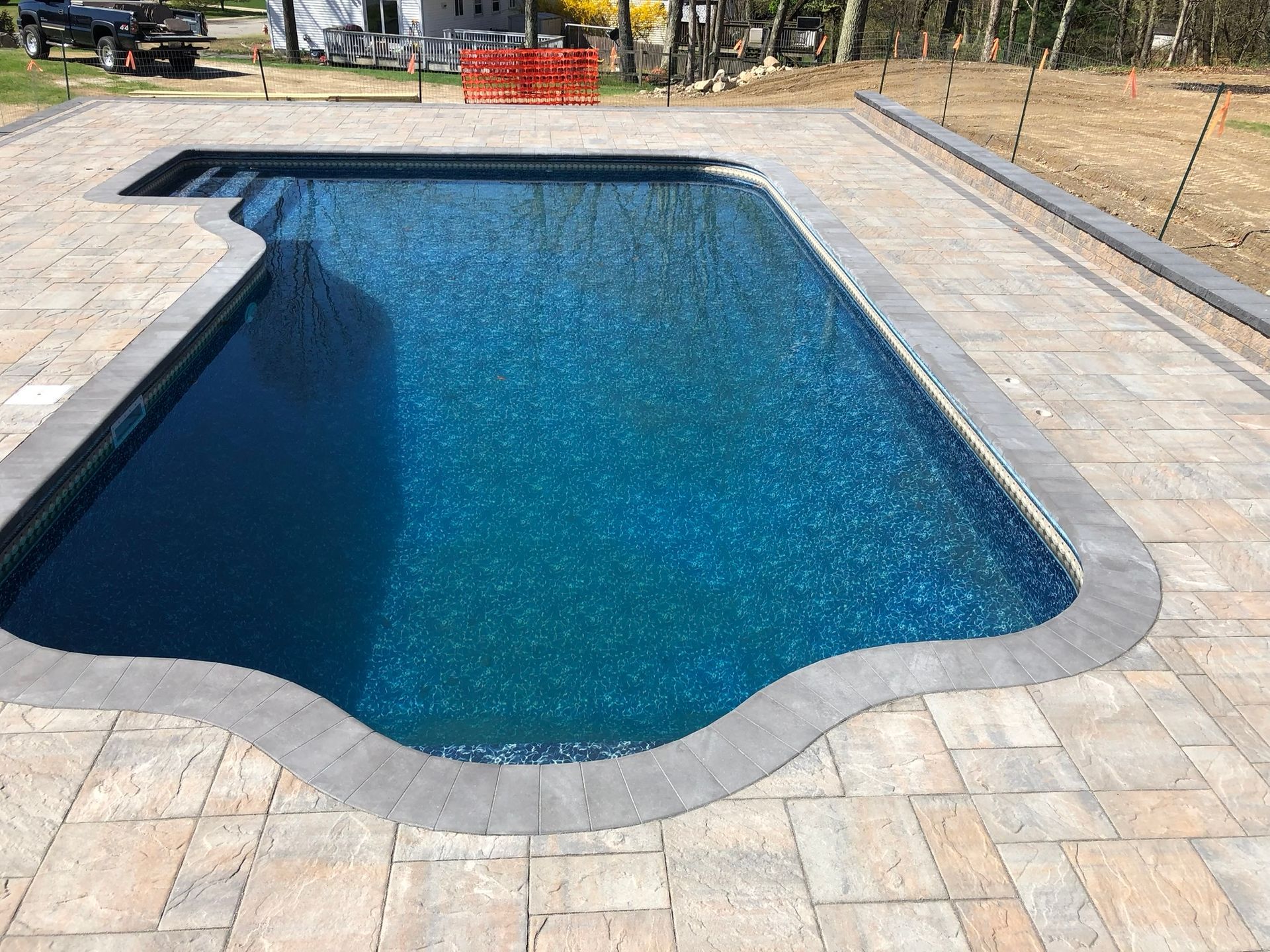 A nice-looking large swimming pool is surrounded by a brick patio.