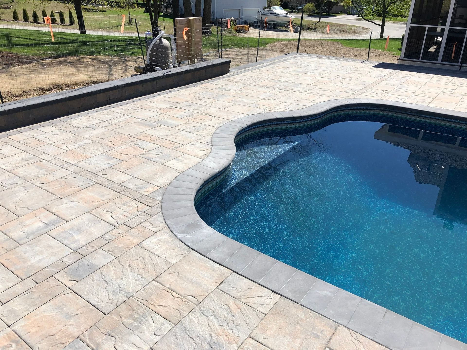 A large swimming pool with a patio in front of it.