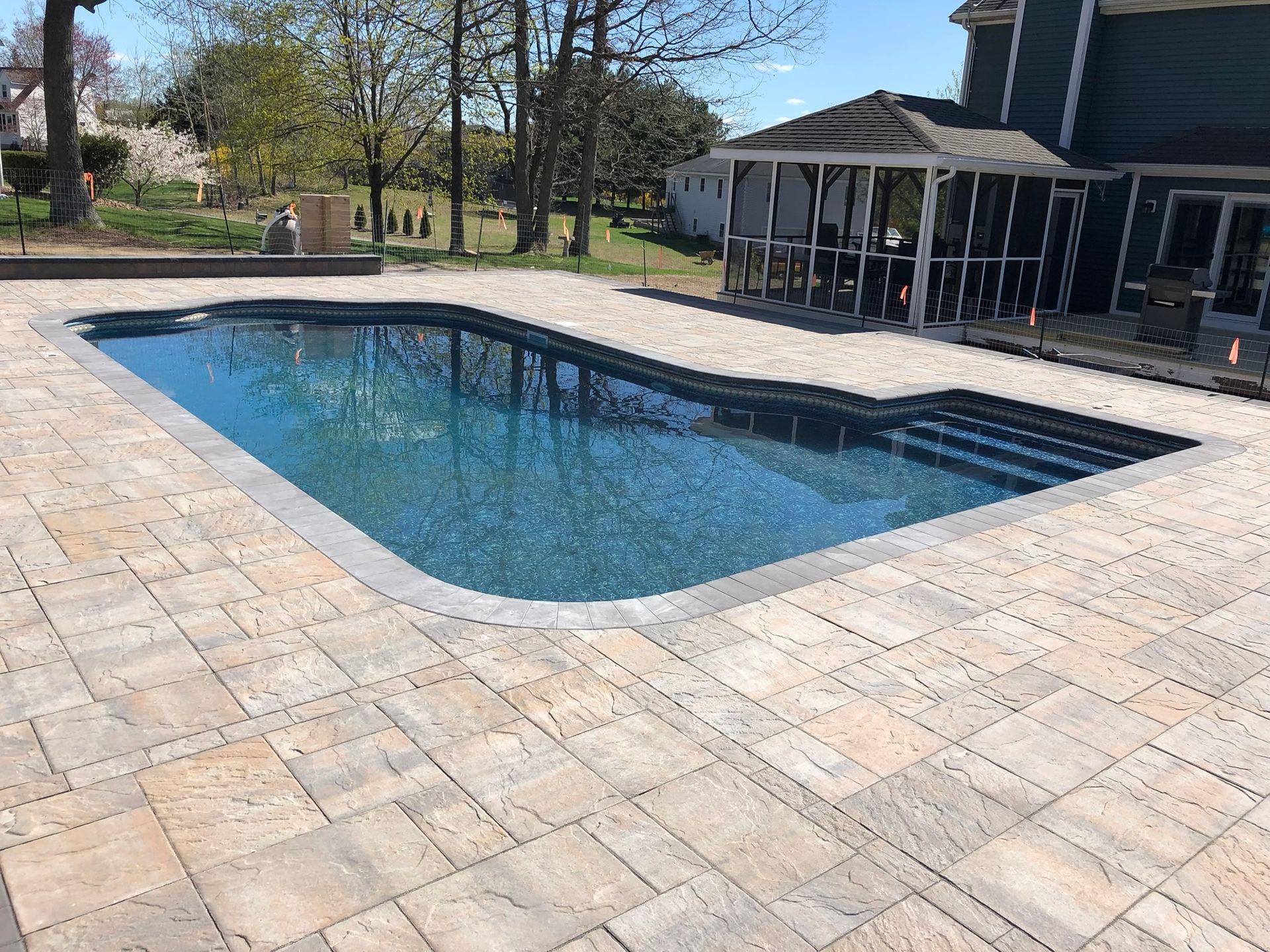 There is a large swimming pool in the backyard of a house.