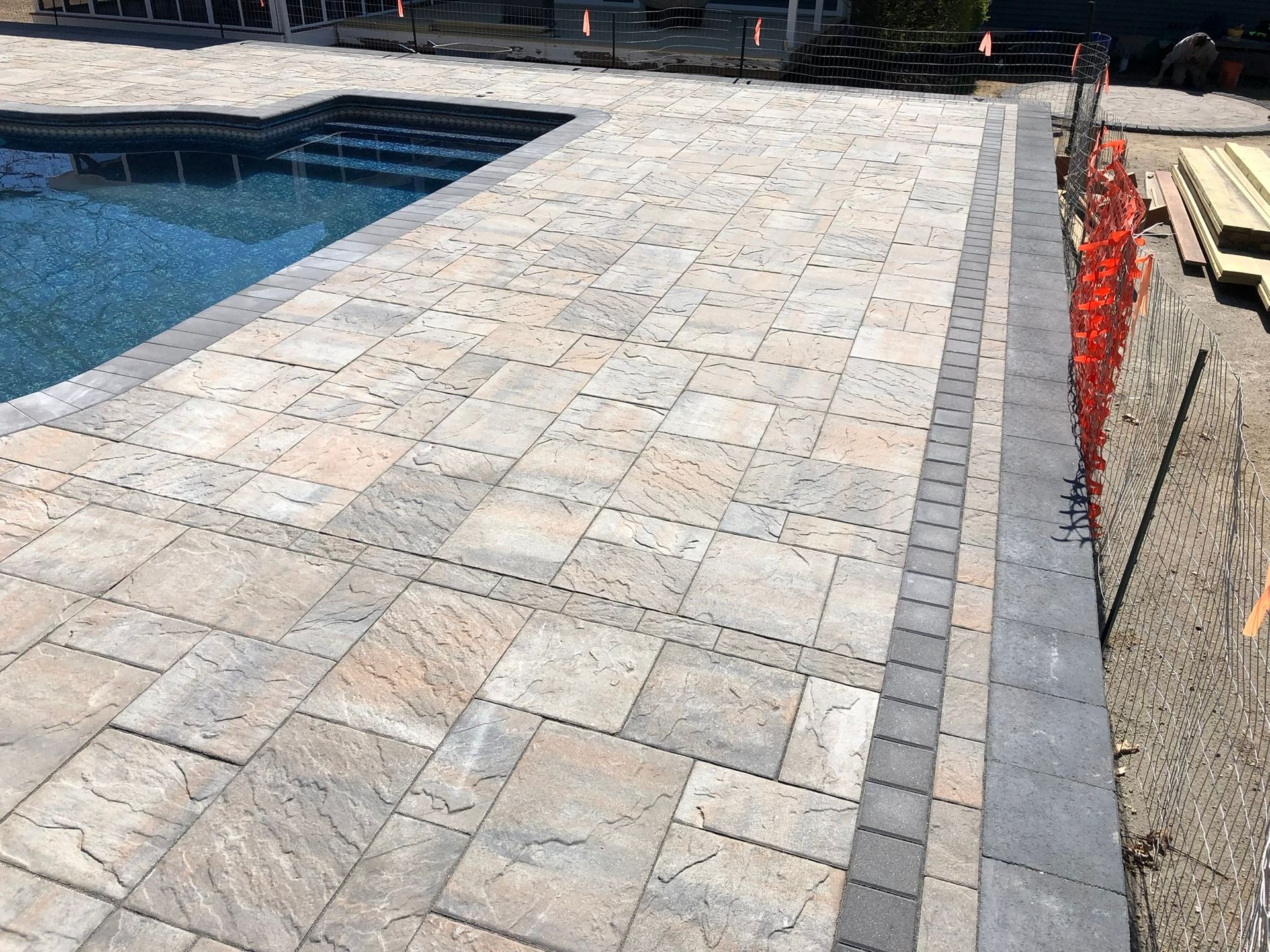 A patio with a swimming pool in the background.