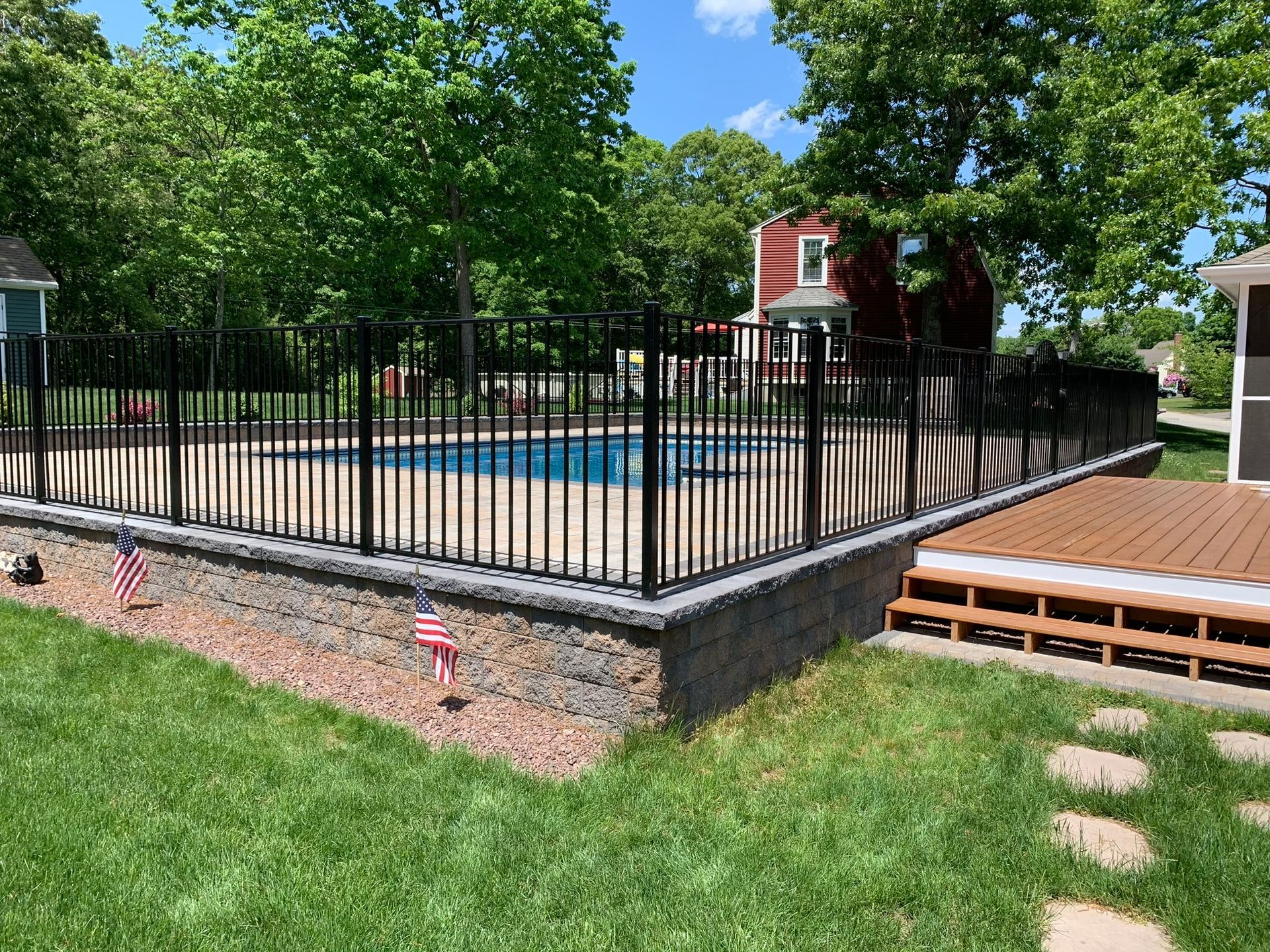 A black fence surrounds a swimming pool in a backyard.