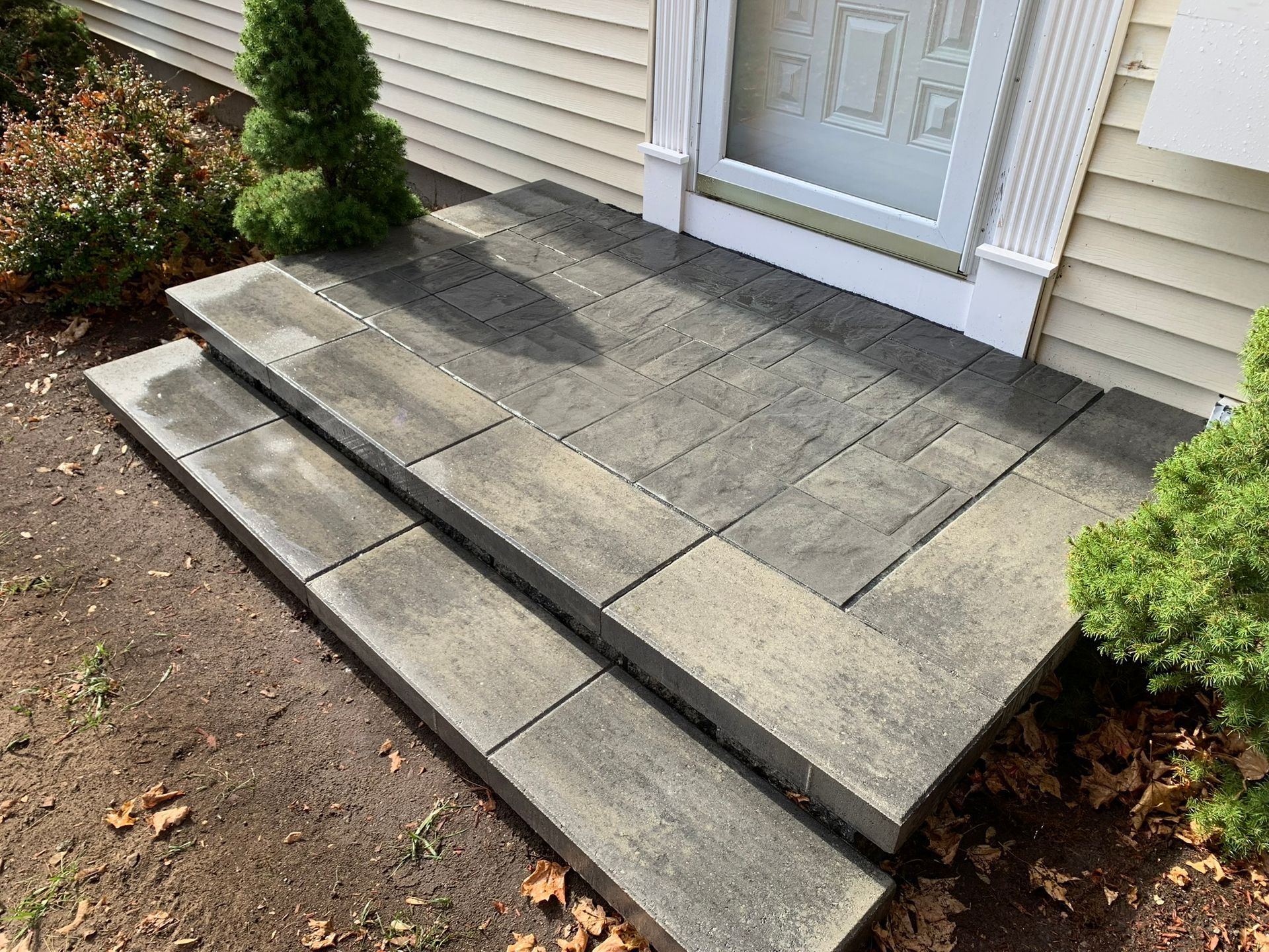 A concrete porch with steps leading to the front door of a house.