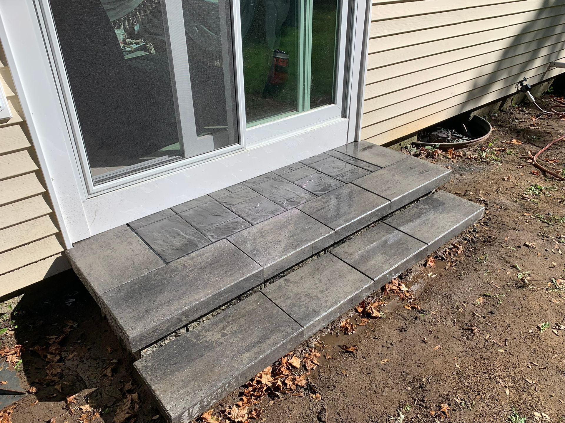 A set of steps leading up to a sliding glass door of a house.