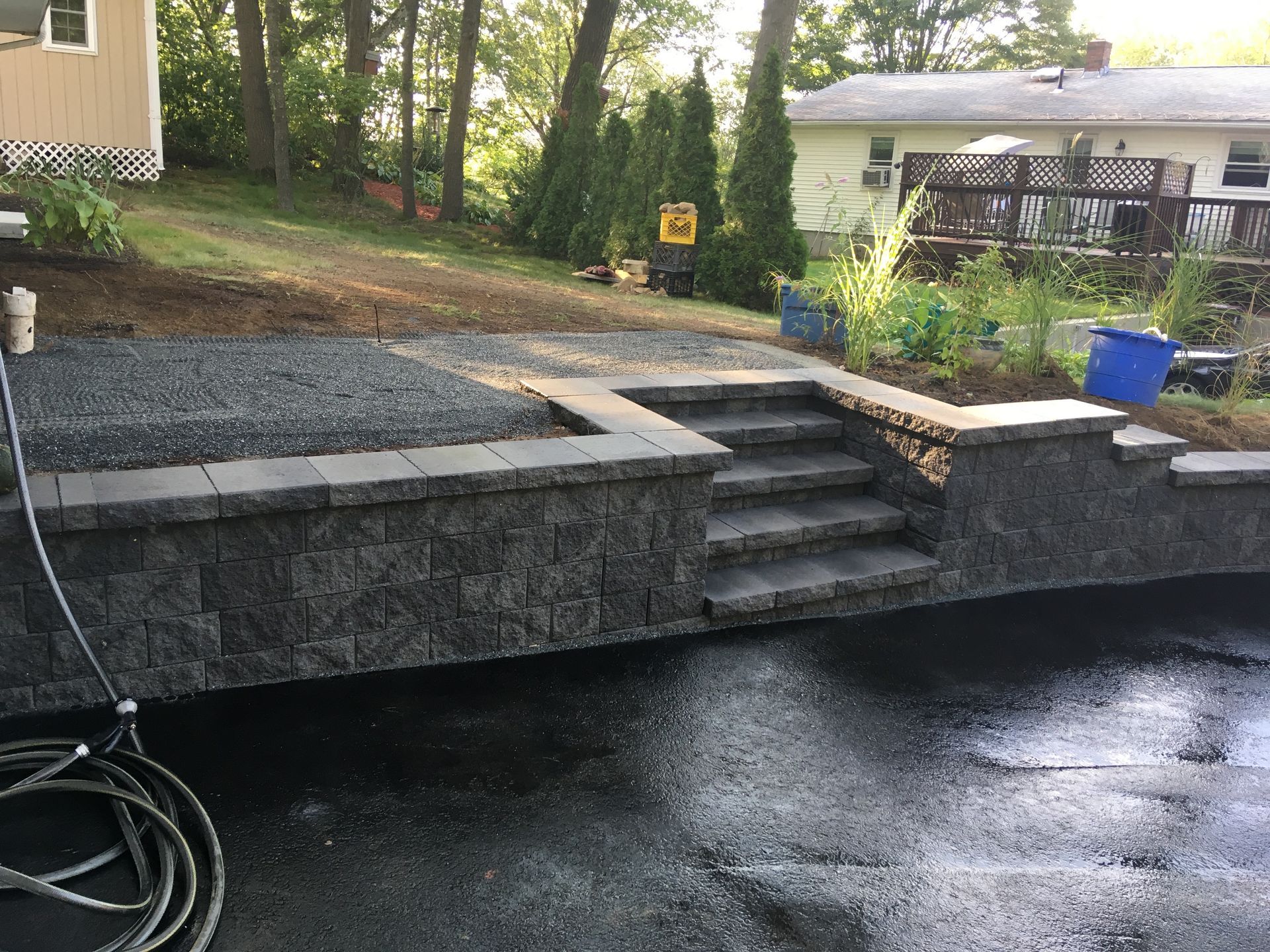 A hose is connected to a wall and stairs in a backyard.