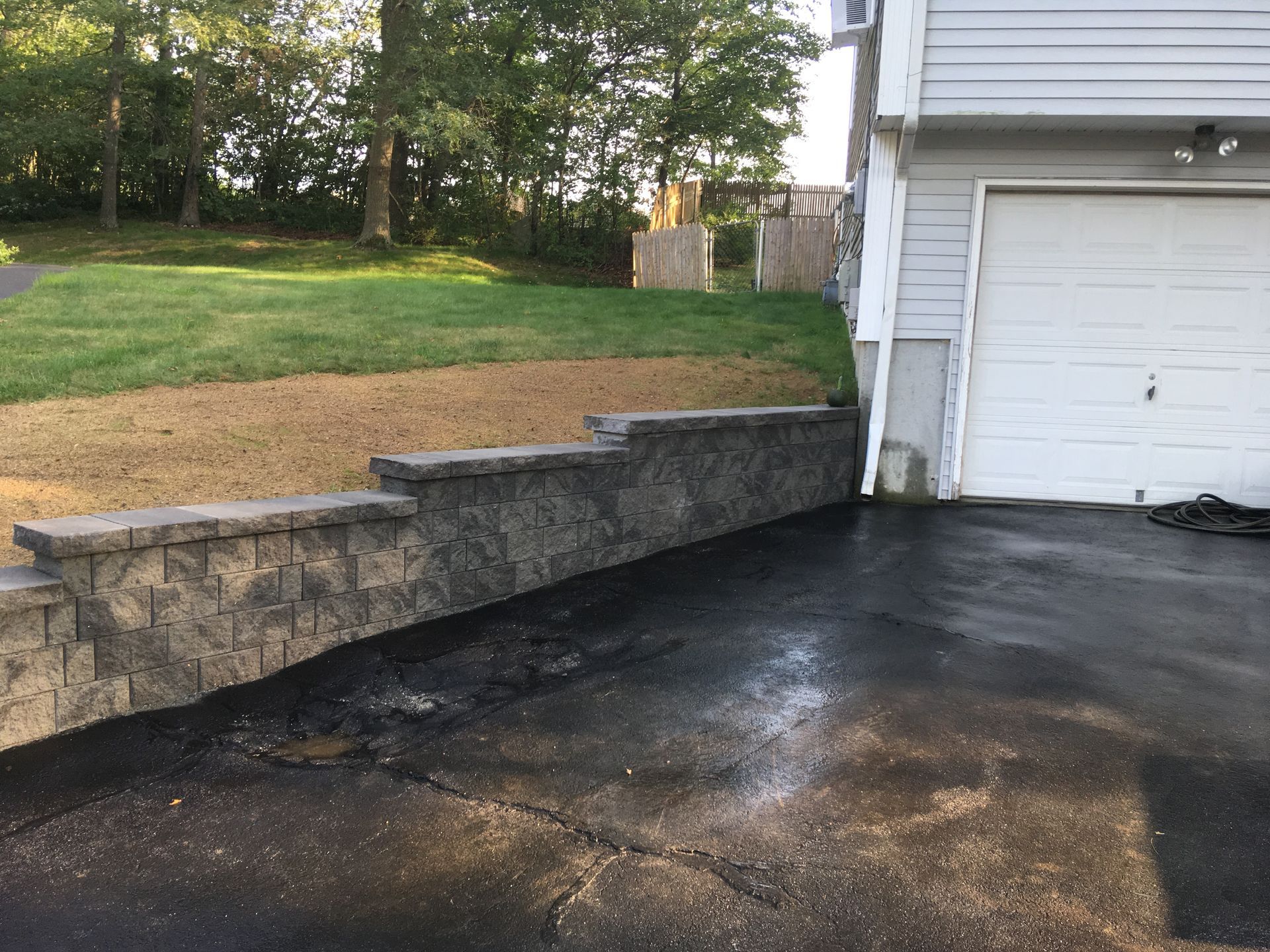 There is a stone wall in the driveway next to the garage.