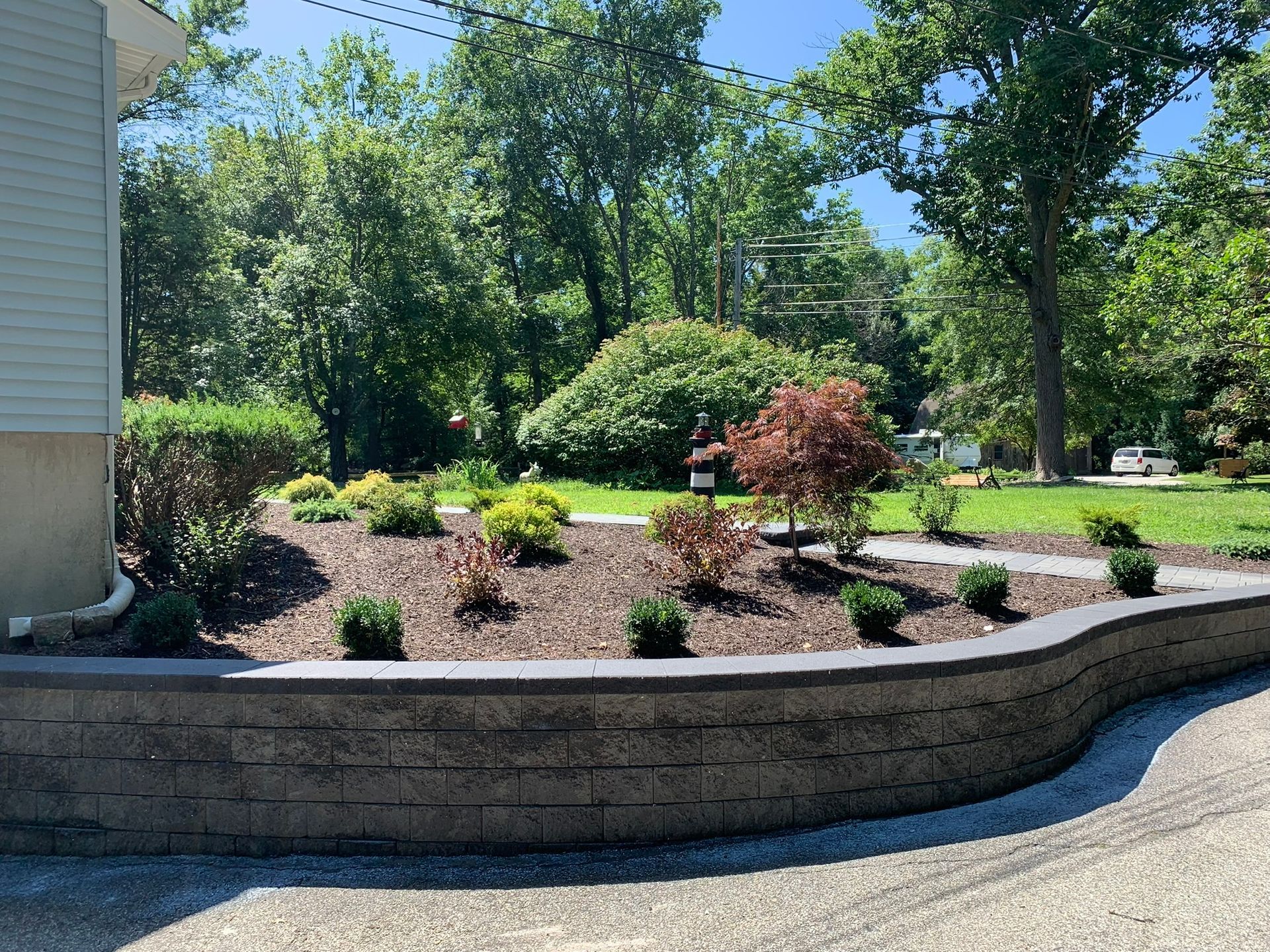 A brick wall surrounds a garden in front of a house.