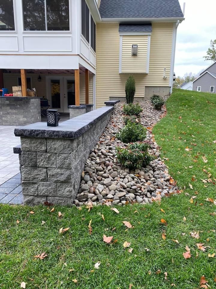 A house with a patio and a stone wall in front of it.