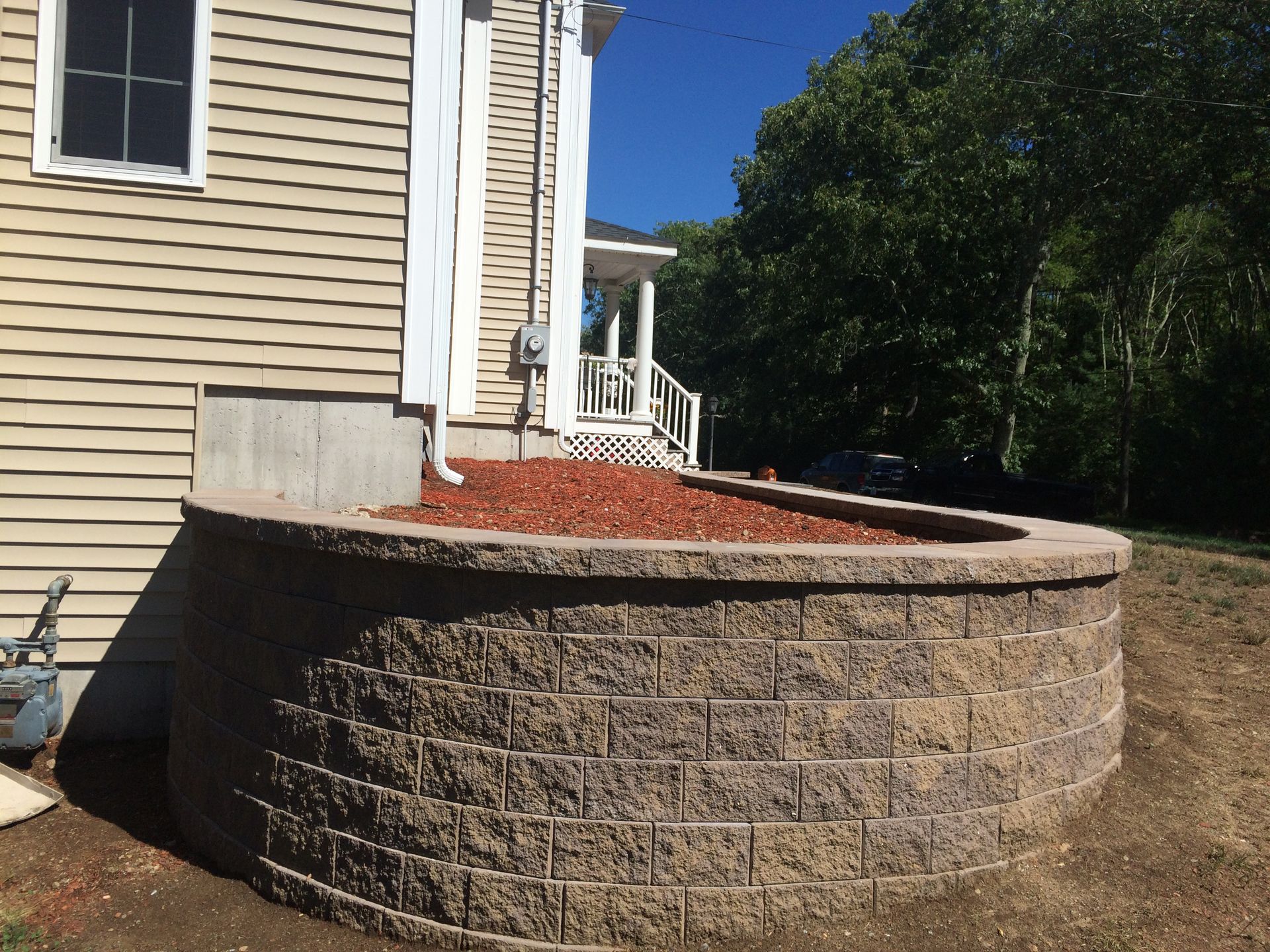 A brick wall is sitting in front of a house.