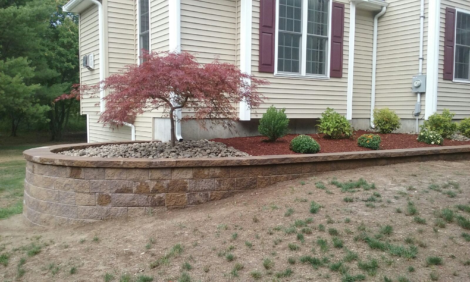 A house with a brick wall and a tree in front of it