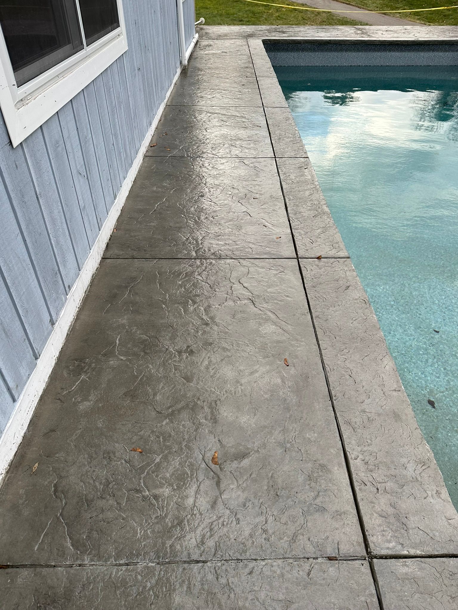 a concrete walkway leading to a swimming pool next to a house .