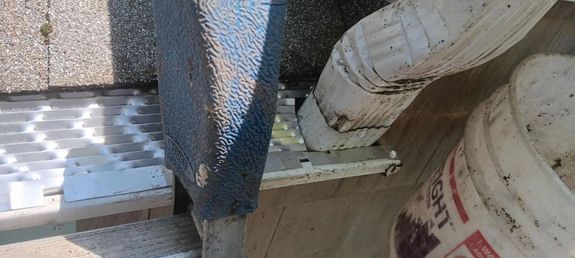 Pallets of white blocks beside a metal mesh fence and a large white bucket in a work area