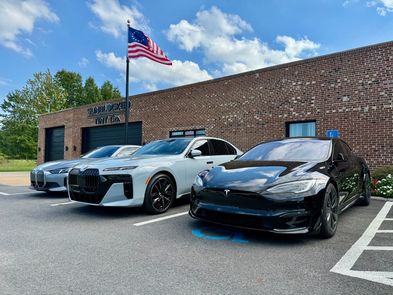 Three sports cars parked in front of a brick building