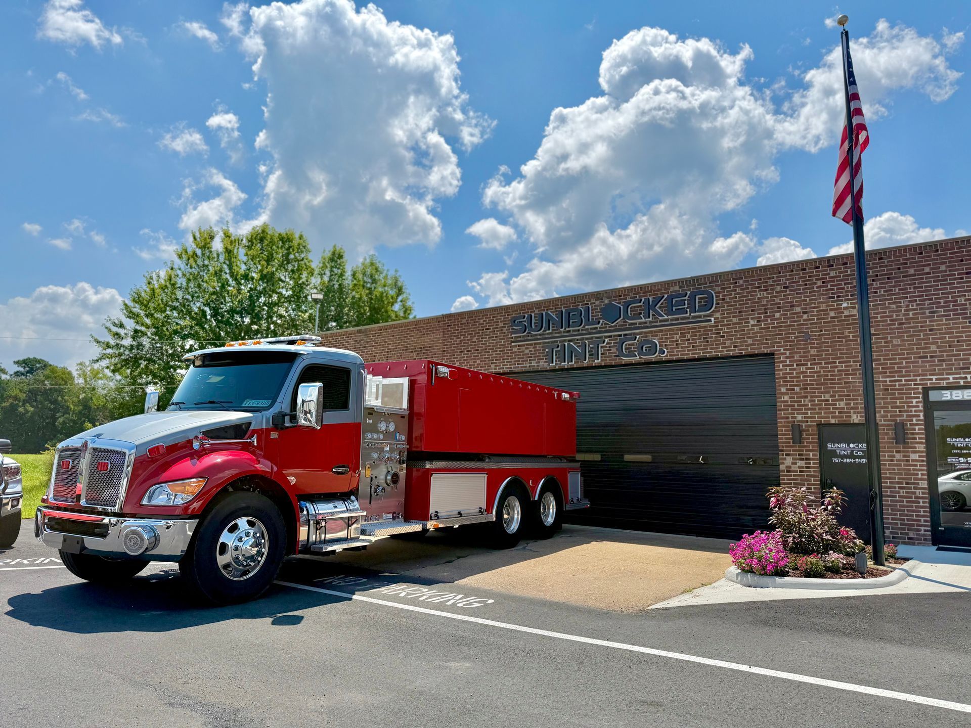 Fire truck parked in front of a brick fire station under a cloudy sky.