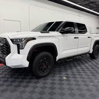 White Toyota pickup truck with black wheels parked indoors.