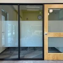 Glass office with frosted privacy bands and a wooden door.