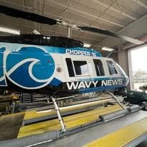 Chopper 30 WAVY News helicopter in a hangar with a blue and white body and logo.